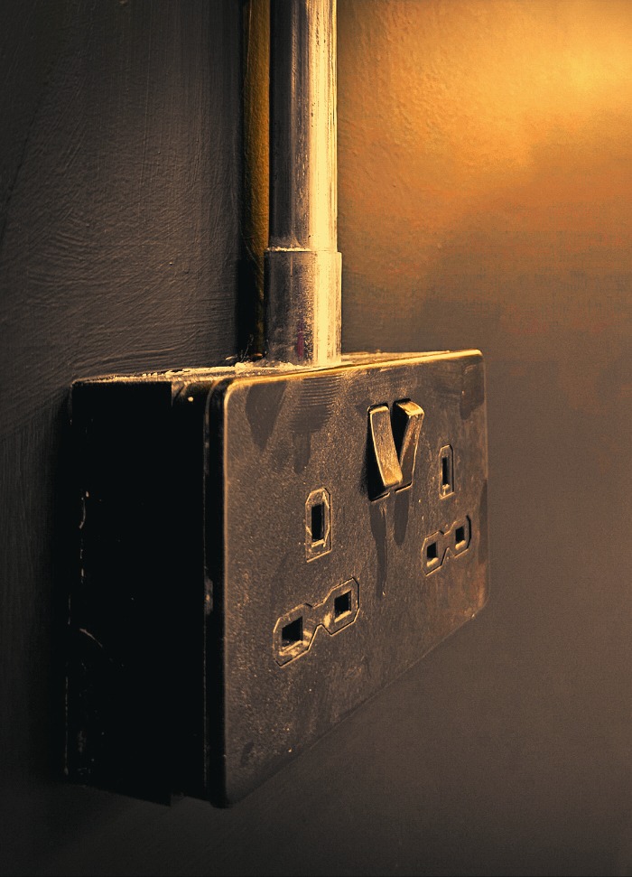 Newly installed metal-clad double socket on a dark hallway wall